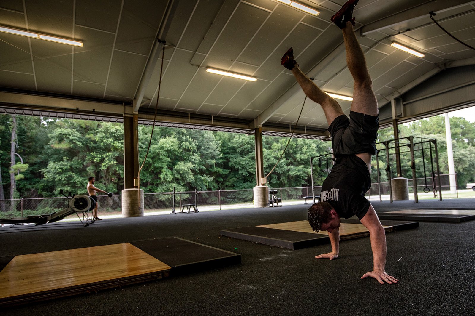 Jerred Moon performing a handstand walk during outdoor garage gym training.